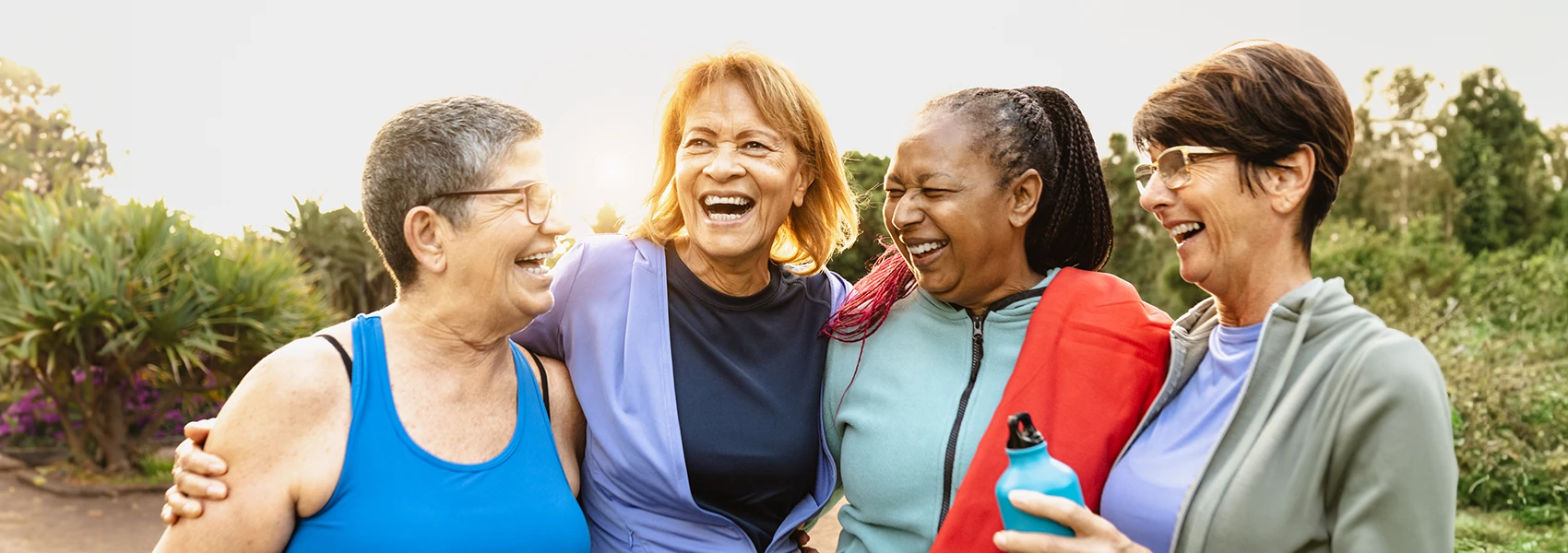 Four women standing shoulder to shoulder outside smiling