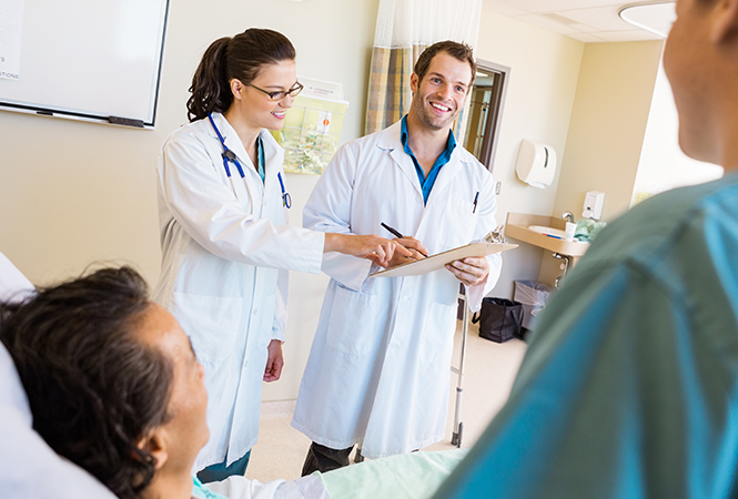 providers in a hospital room speaking to a woman and man sitting